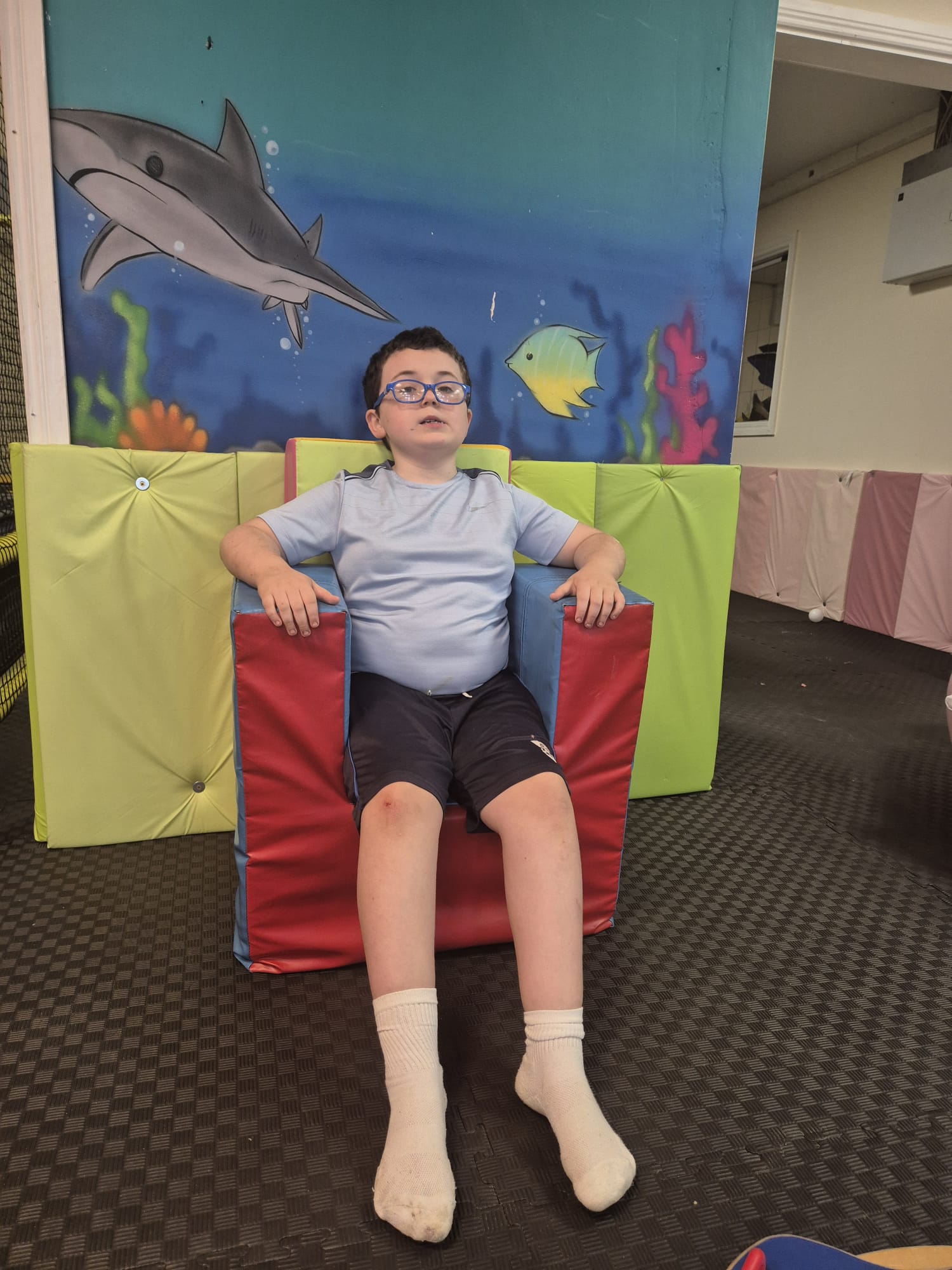 A boy relaxing in a colourful soft chair in the sensory room at the ASD Ireland summer camp.