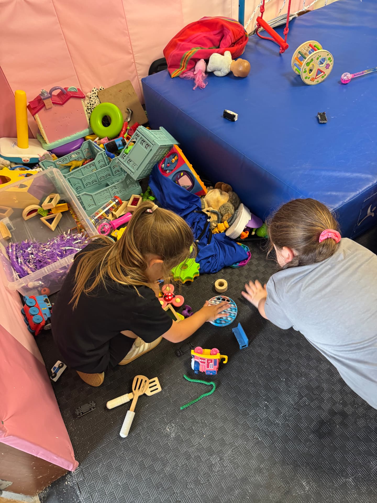 Two girls playing with sensory toys on soft flooring at the ASD Ireland camp.