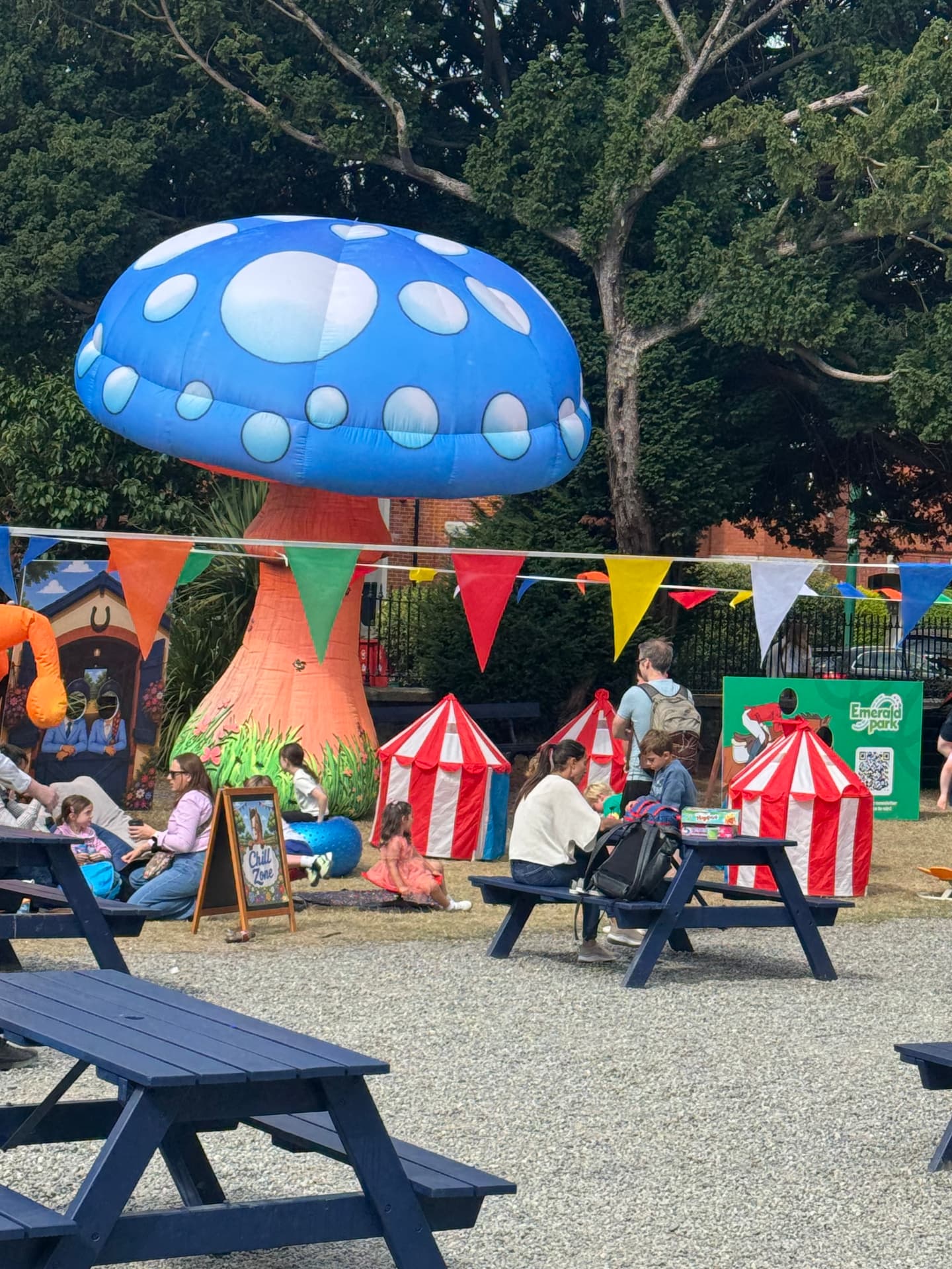 The chill-out zone at an outdoor family event, with a giant inflatable mushroom, bunting and picnic tables.