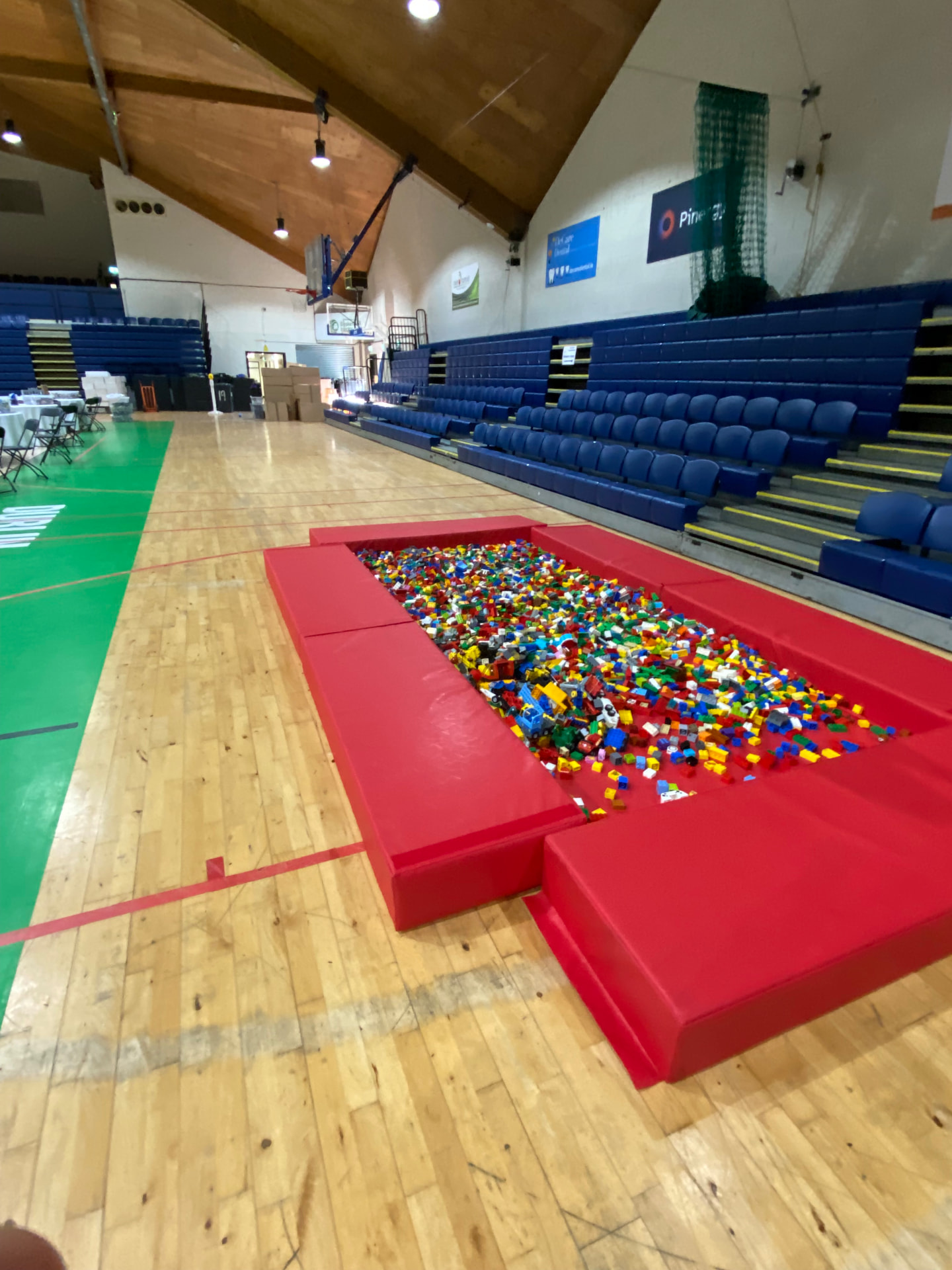 Inside the National Basketball Arena set up for Dublin Brickcon, with a giant pit of colourful building bricks on the court and tiered seating behind.