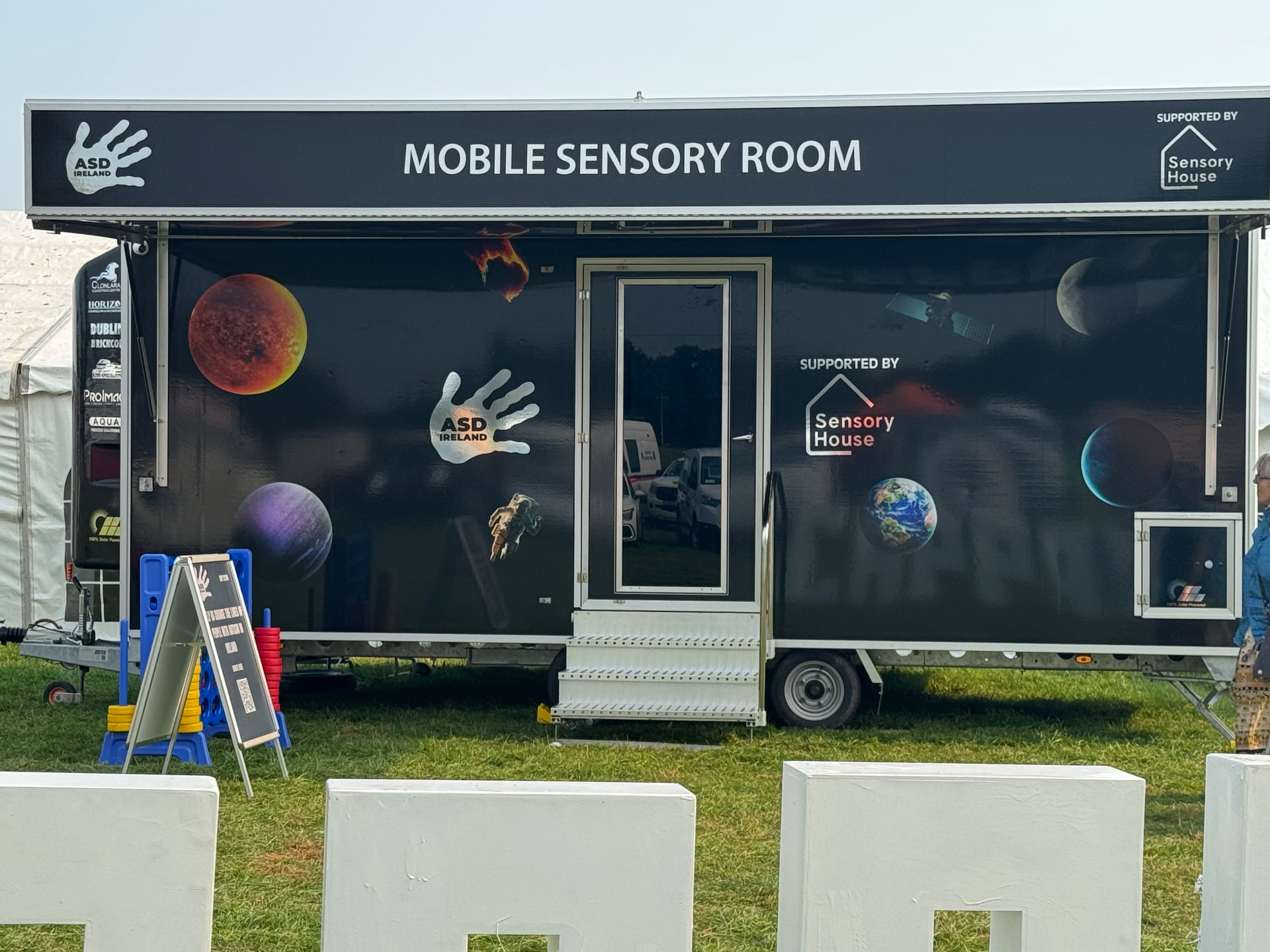 The ASD Ireland mobile sensory room trailer parked on grass, with official ASD Ireland branding and sensory decorations.
