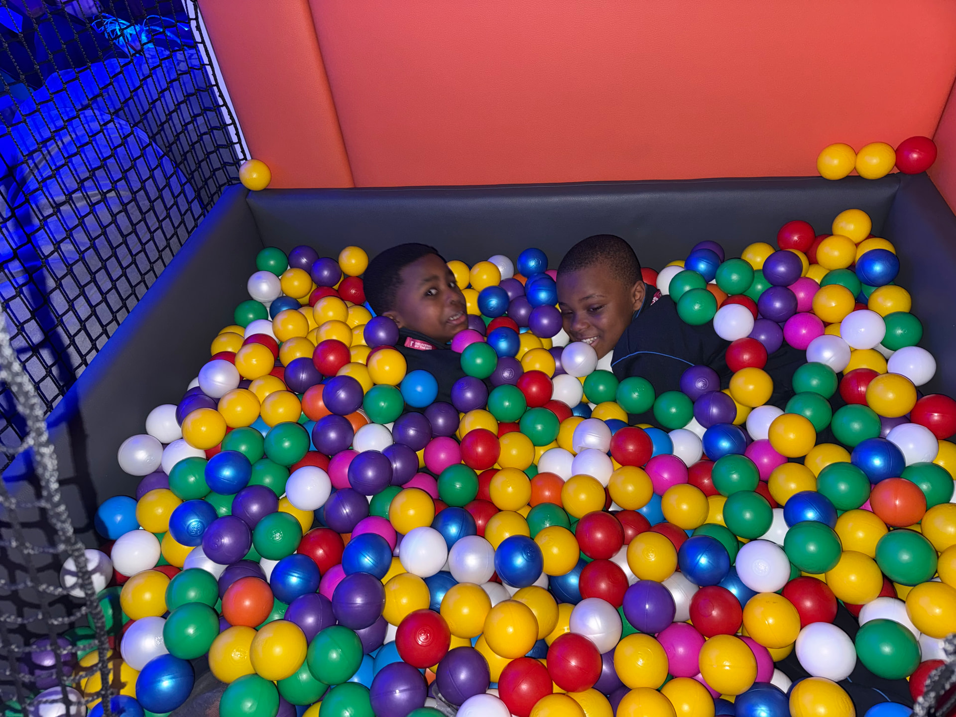 Two laughing boys shoulder-deep in the colourful ball pit inside the mobile sensory room.