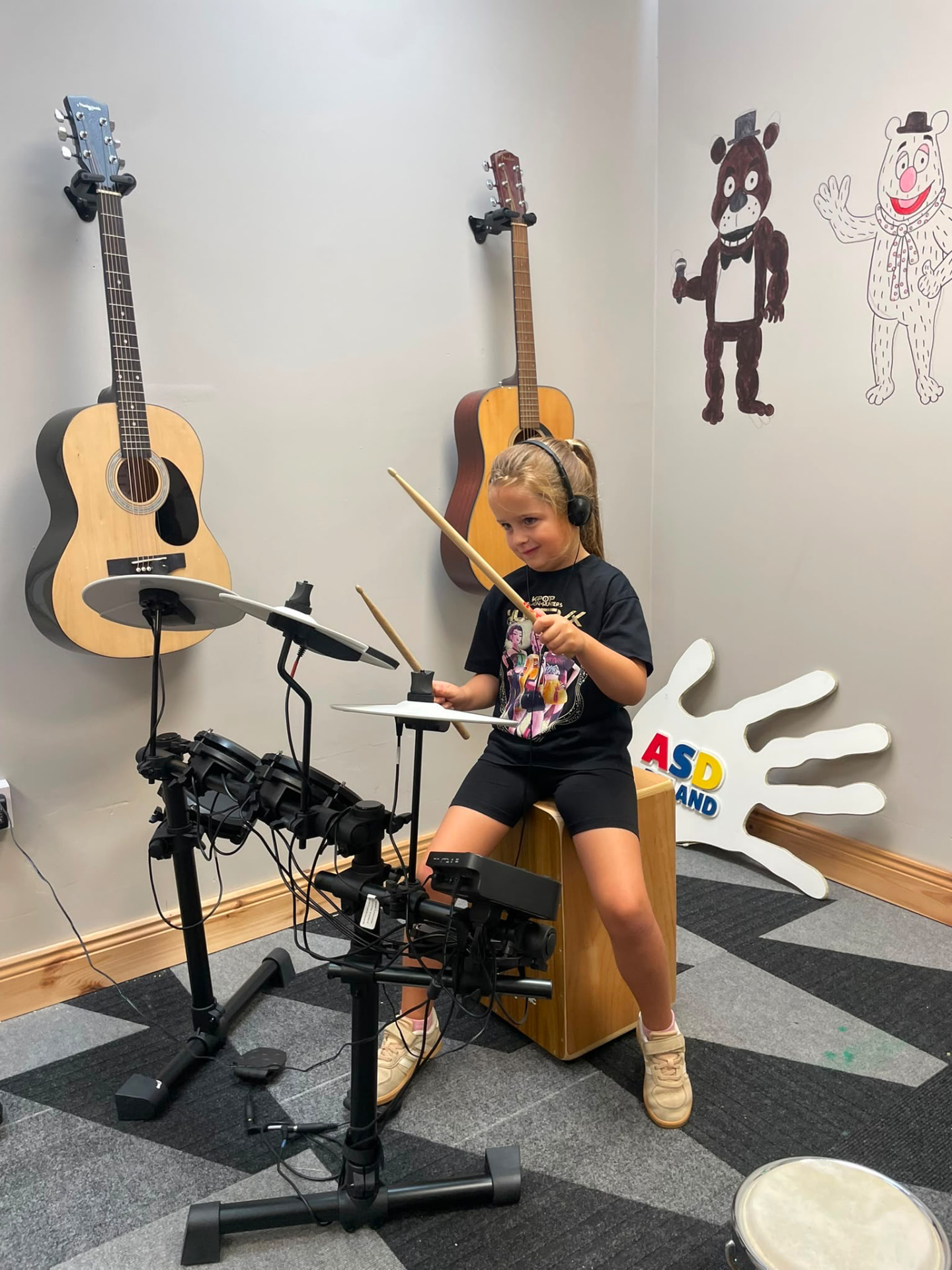 A young girl playing an electronic drum kit at the ASD Ireland summer camp music room.