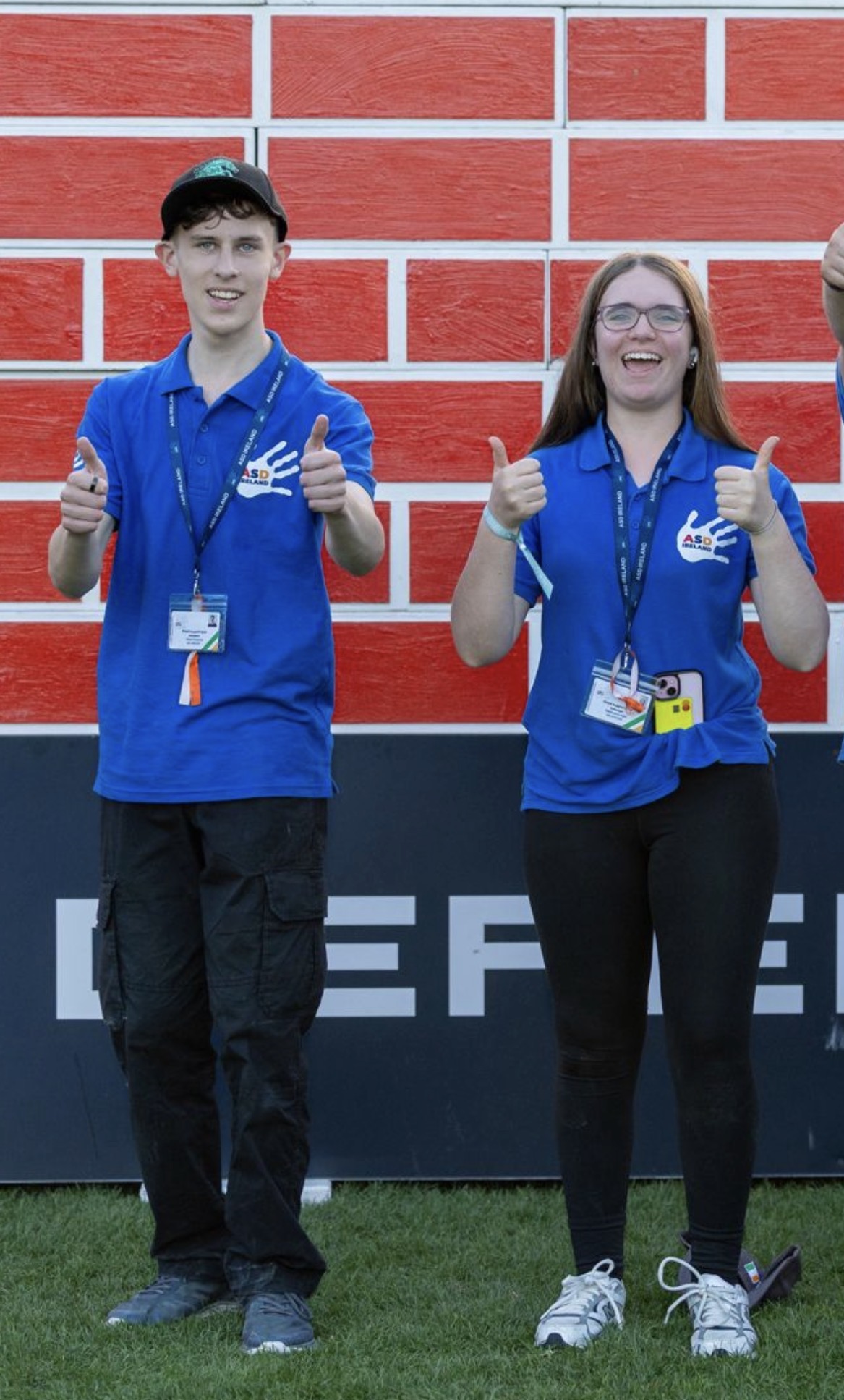 Two ASD Ireland volunteers in blue polo shirts giving a thumbs up at the Dublin Horse Show.