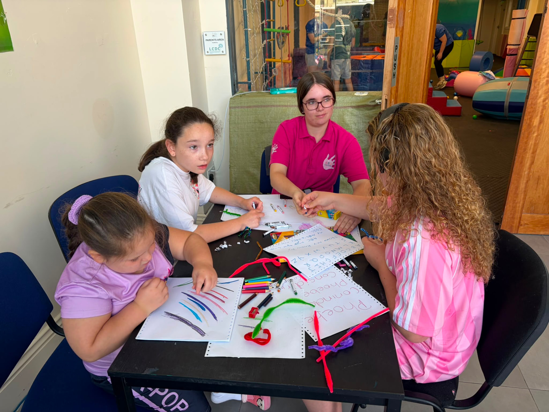 Children drawing and colouring together at a table during the ASD Ireland summer camp.
