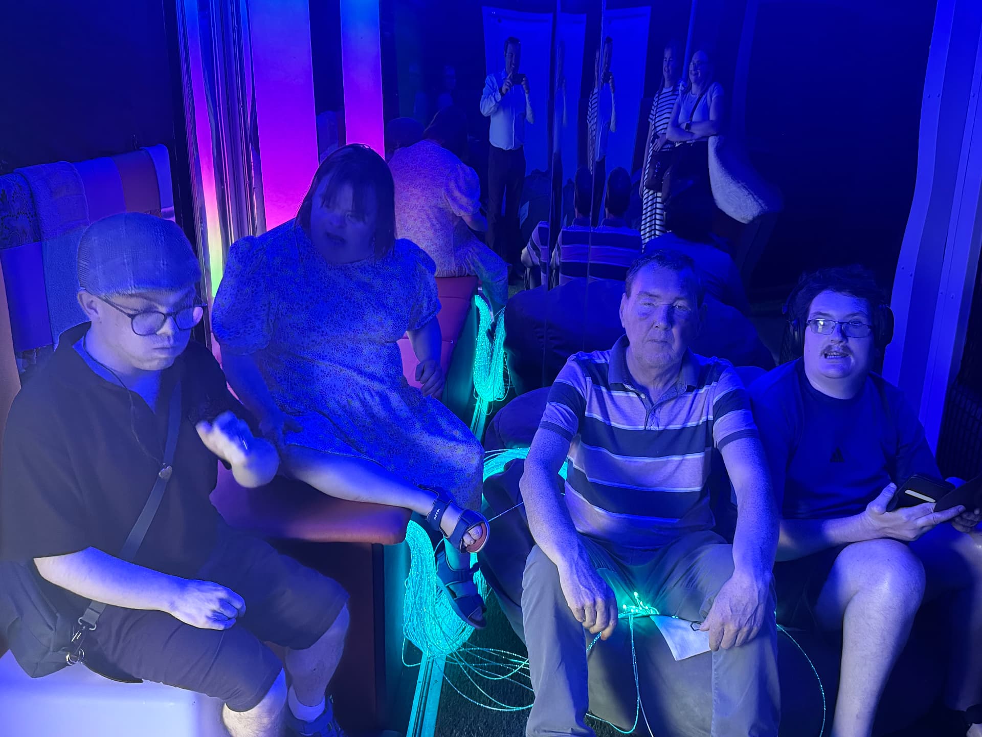 Adults and visitors relaxing inside the softly lit mobile sensory room.